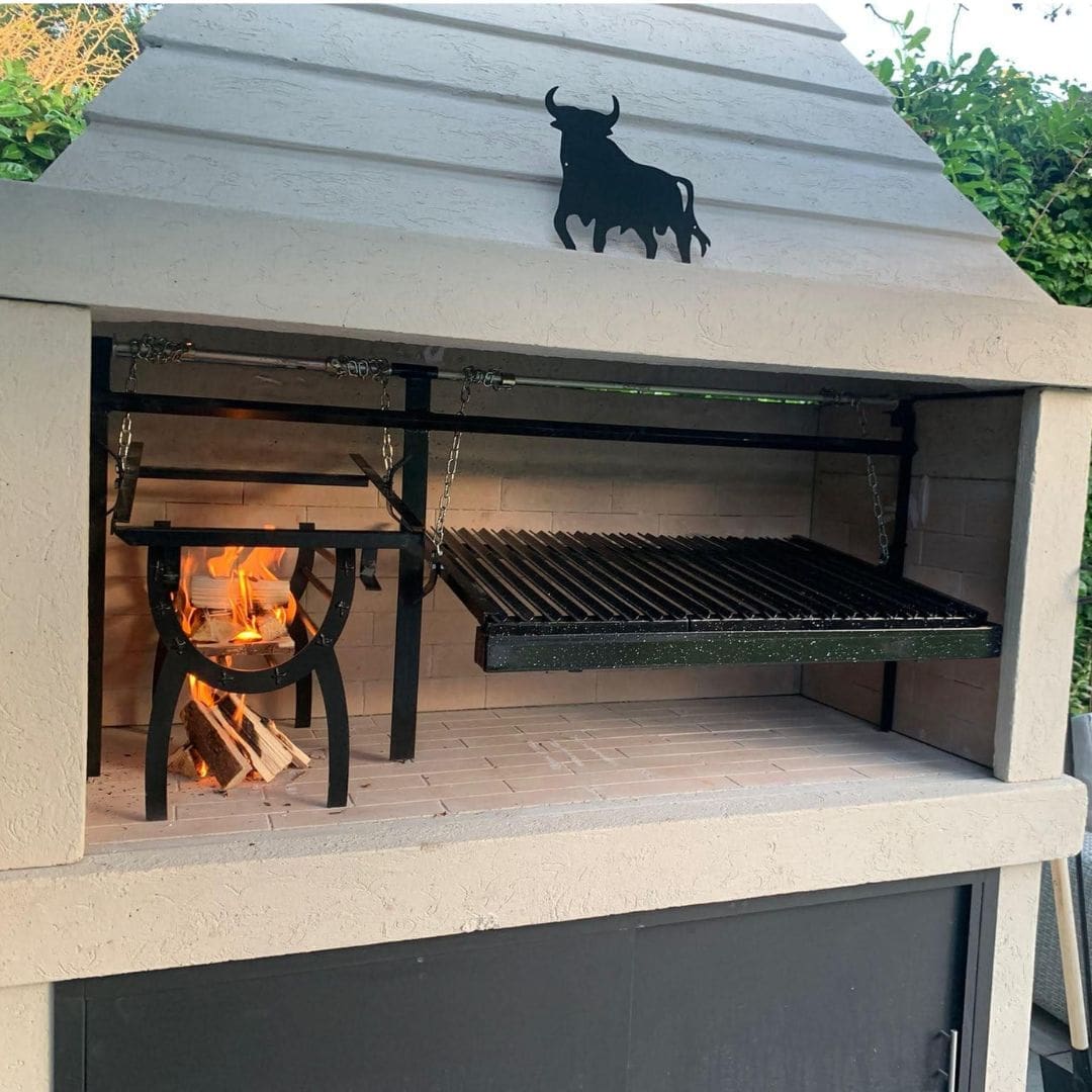 Outdoor barbecue Argentinian grill with a bull emblem and a fire burning inside.